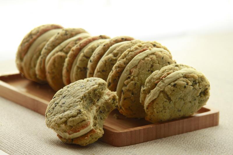 Row of matcha brown butter sandwich cookies on wooden board