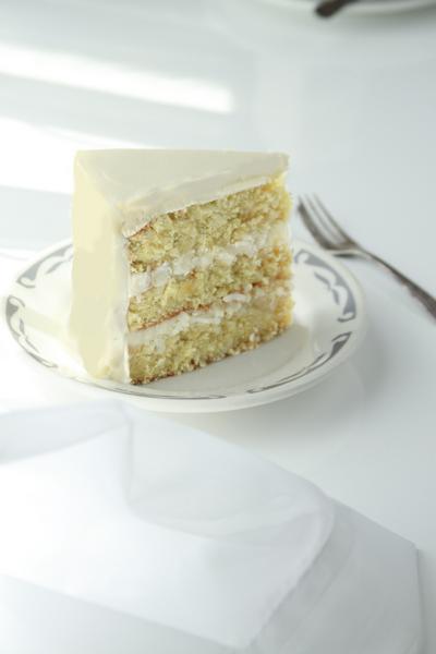 Slice of Savannah Coconut Cake on glass plate with fork