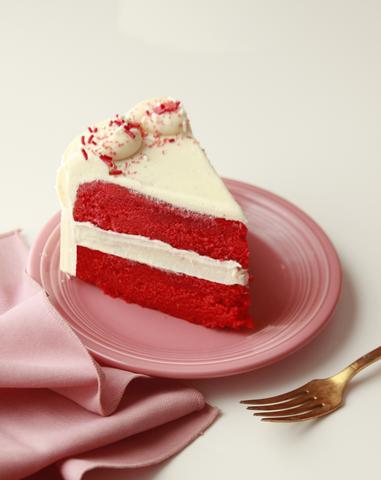 Red velvet cake slice with visible layers on a pink plate